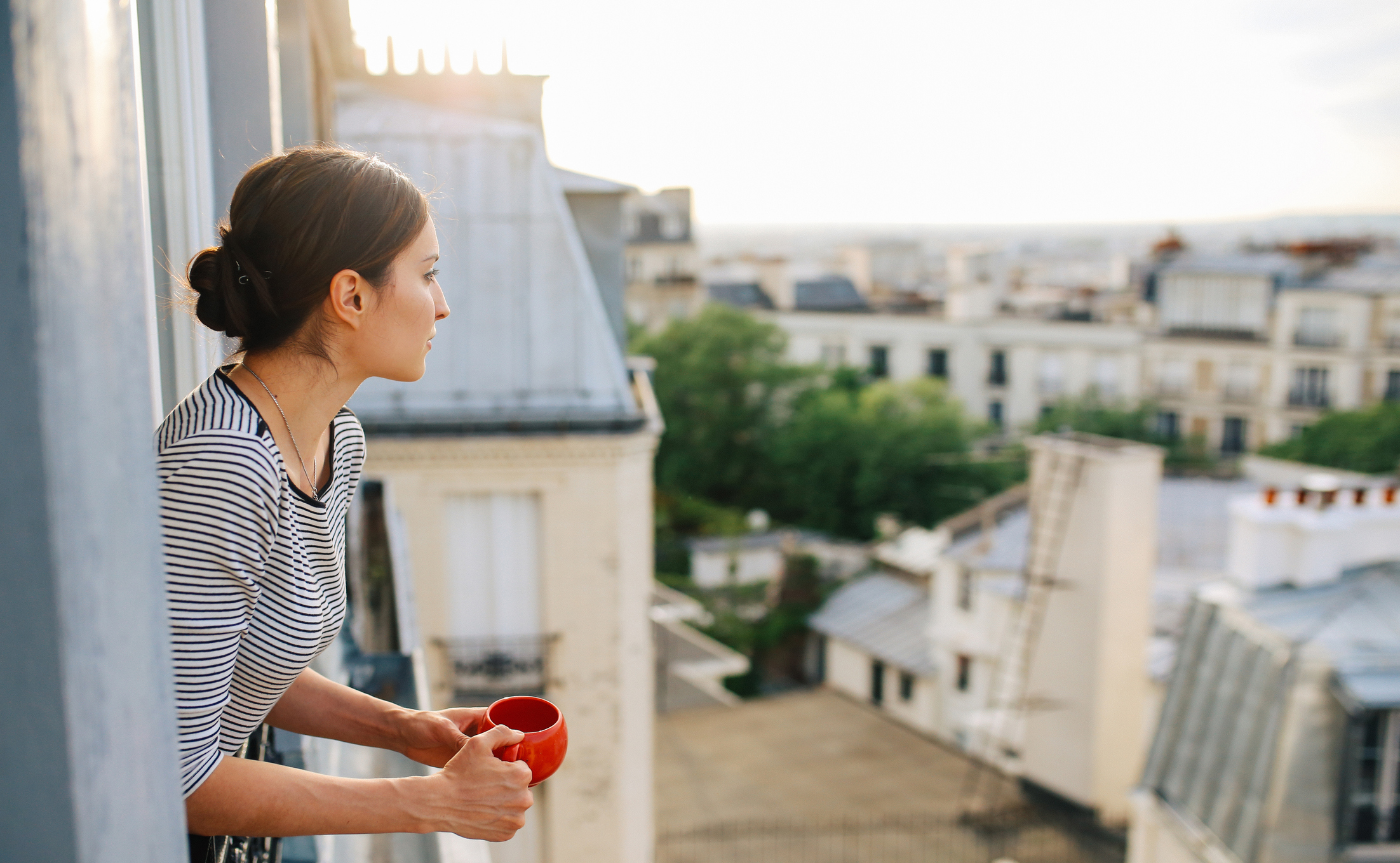 Jeune femme profitant de la vue depuis un appartement parisien